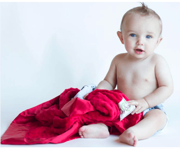 Baby sitting up with a red MyBlankee blanket