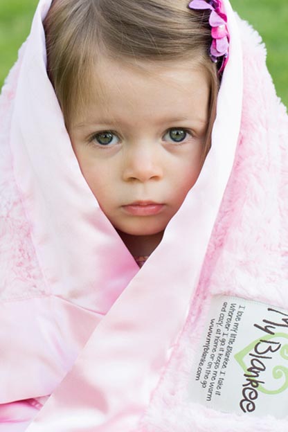 Girl looking out of a pink blanket