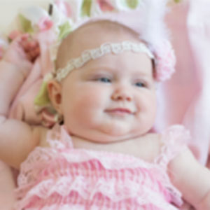 Smiling baby in pink laying on a pink blanket