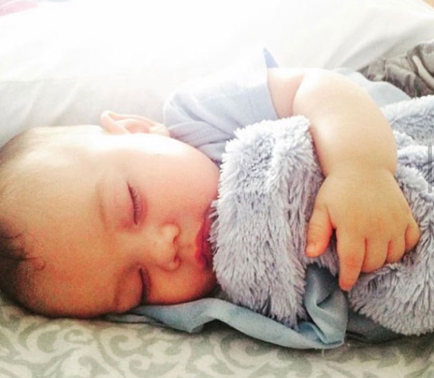 Baby sleeping holding on a grey blanket